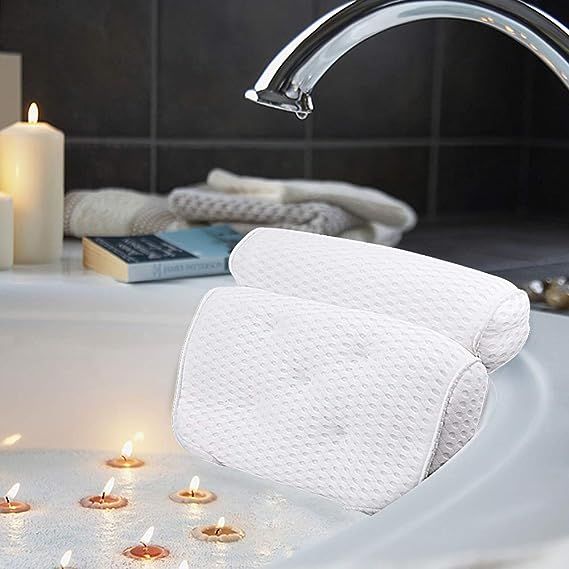a photo of a white mesh bath billow with candles floating in the water and a book nearby