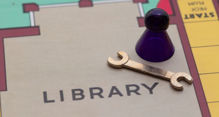 a board game with a game piece, a small silver wrench placed in a section labeled "library"