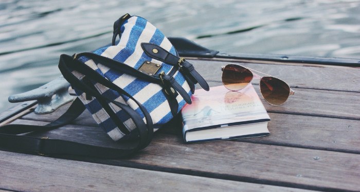 a photo of a book, bag, and sunglasses on a dock