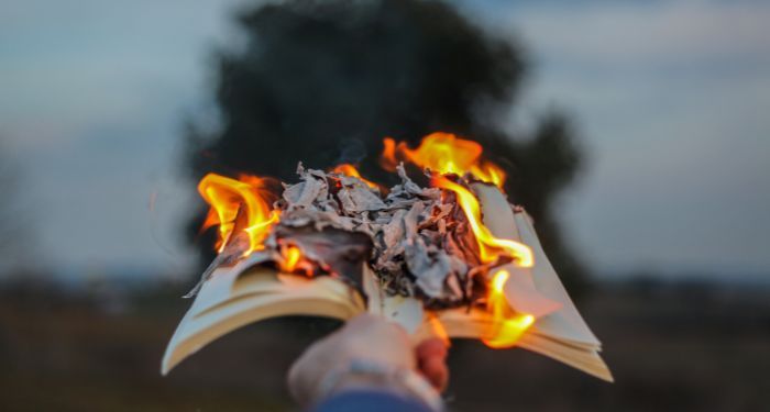 Image of a hand holding out a book on fire