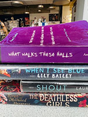 a photo of book spine poetry spelling out "What walks these halls / when I see blue / shout / the deathless girls"