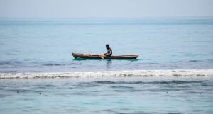 Dark brown-skinned man riding on brown boat on sea during daytime in Haiti