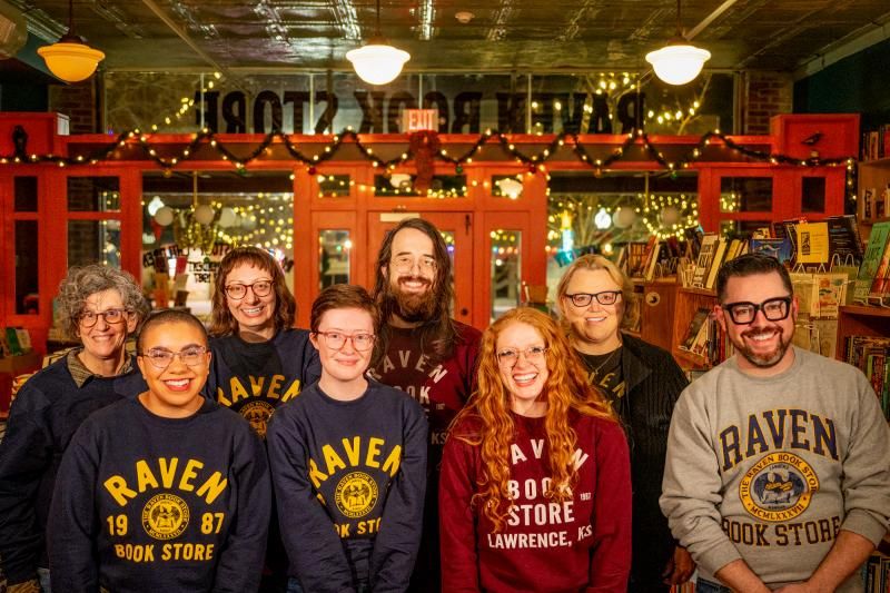 A photo of eight people in Raven Book Store sweatshirts posing in the book store