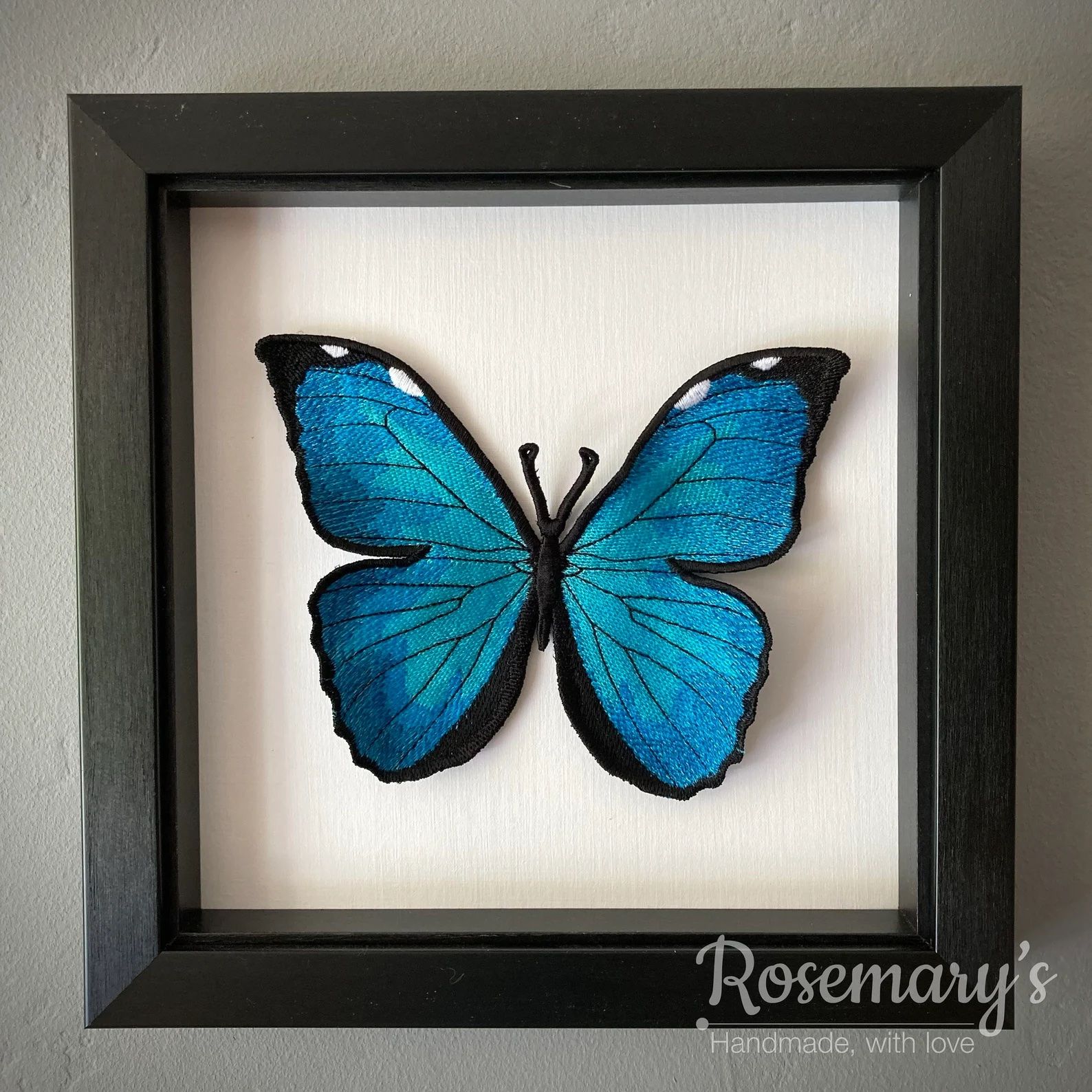 a 3d embroidered blue butterfly in a shadowbox