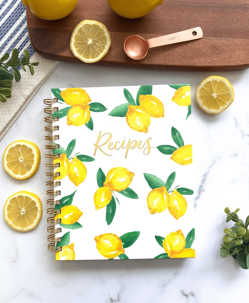 Image of a white notebook with lemons painted on it and the text recipes at the centre