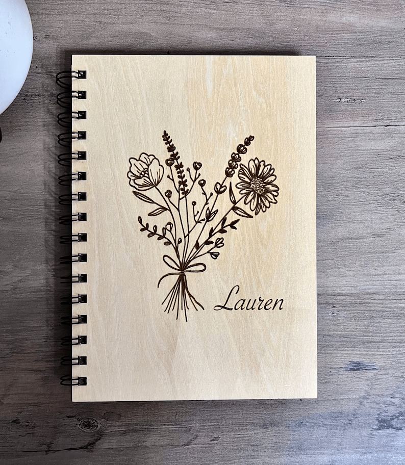 A notebook with a wooden cover and flowers engraved on it