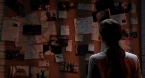 person looking at a wall full of papers and pictures that look like clues