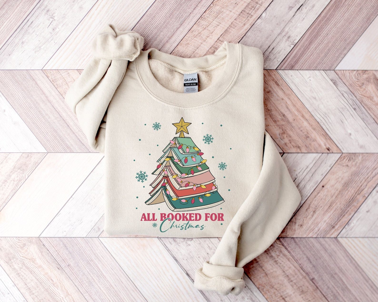 an off-white sweatshirt with a tree made out of books and the words "All booked for Christmas"