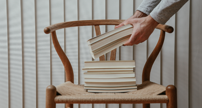 a photo of someone putting a stack of books on a chair