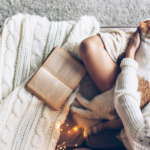 a photo of someone reading on the couch with a cat