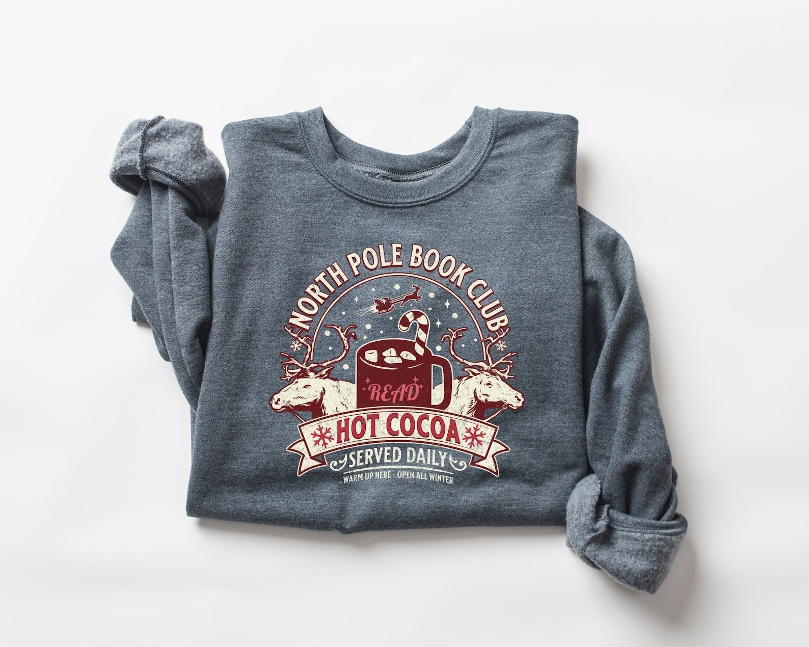 A blue sweatshirt with a cosy picture of the North Pole and the words "North Pole Book Club"
