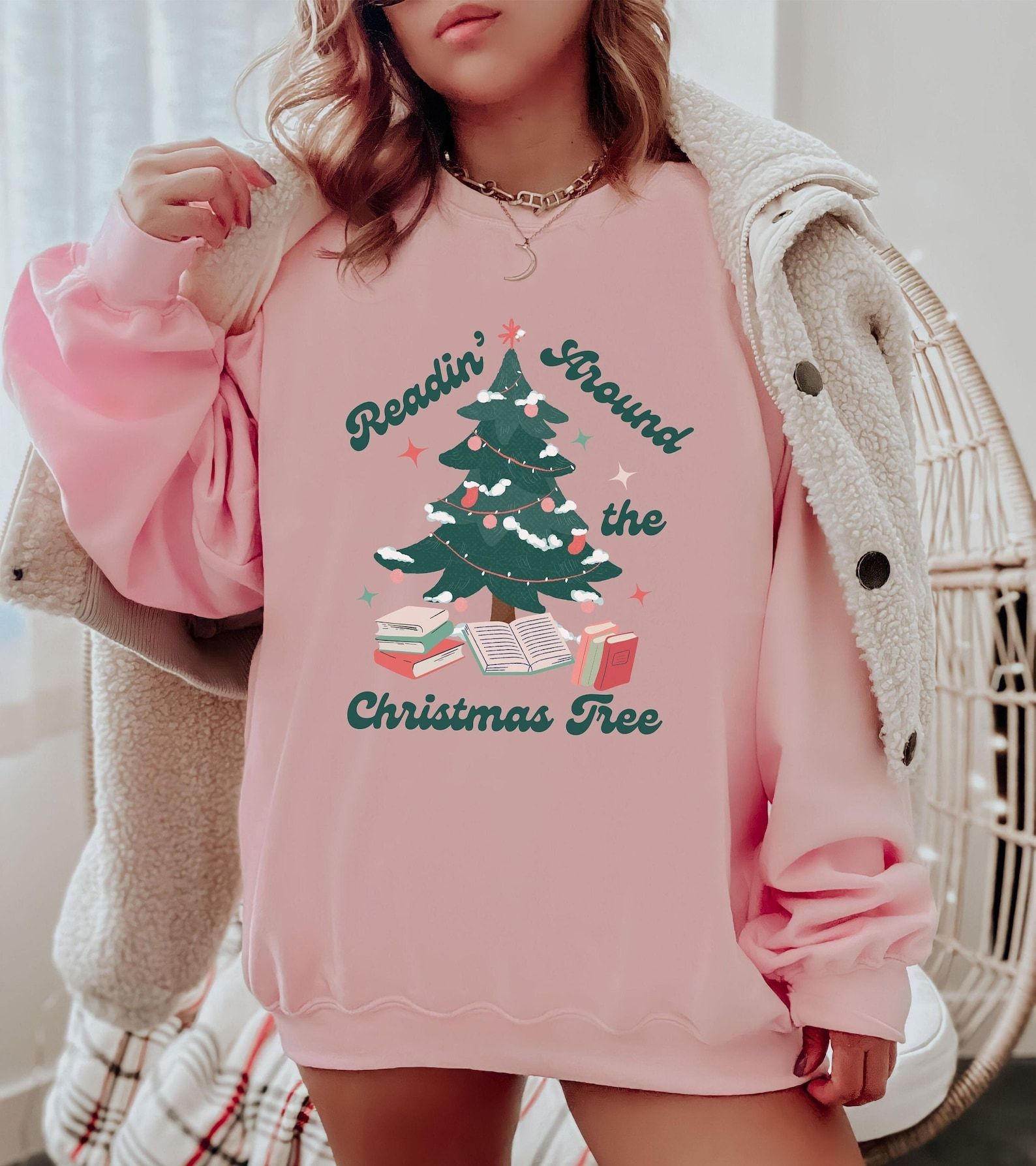A pink sweatshirt with a decorated Christmas tree, books beneath it, and the words "Readin' around the Christmas tree"