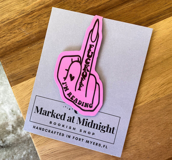 a hot pink bookmark shaped like a hand giving the middle finger that says "fuck off I'm reading"