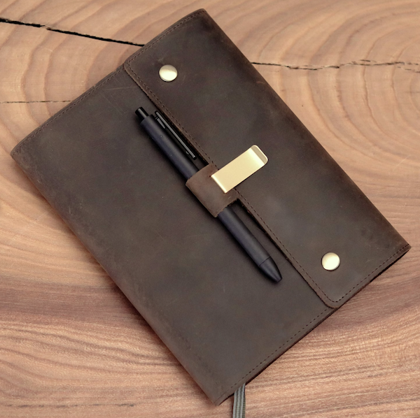 A notebook cover in brown leather with a loop for a pen.
