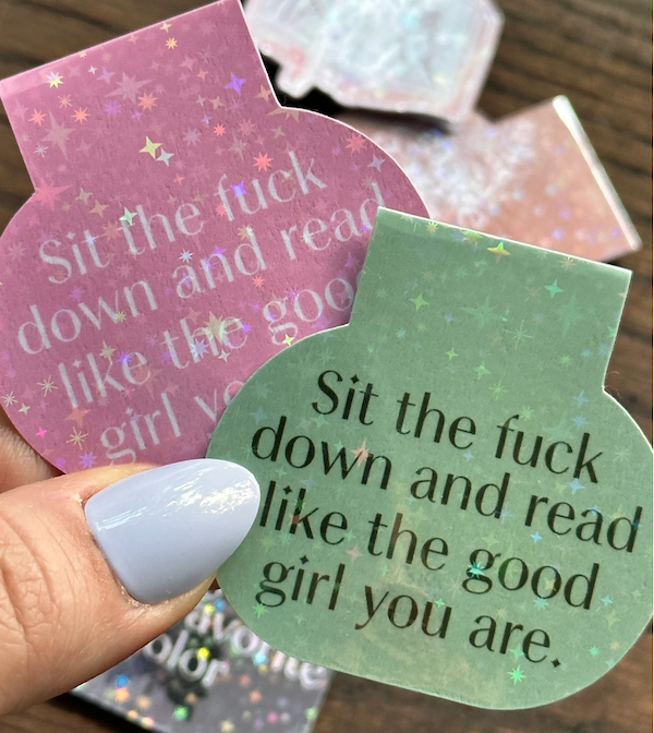 a magnetic bookmark in green or pink that says "sit the fuck down and read like the good girl you are"