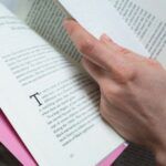 Image of a white hand holding open a book