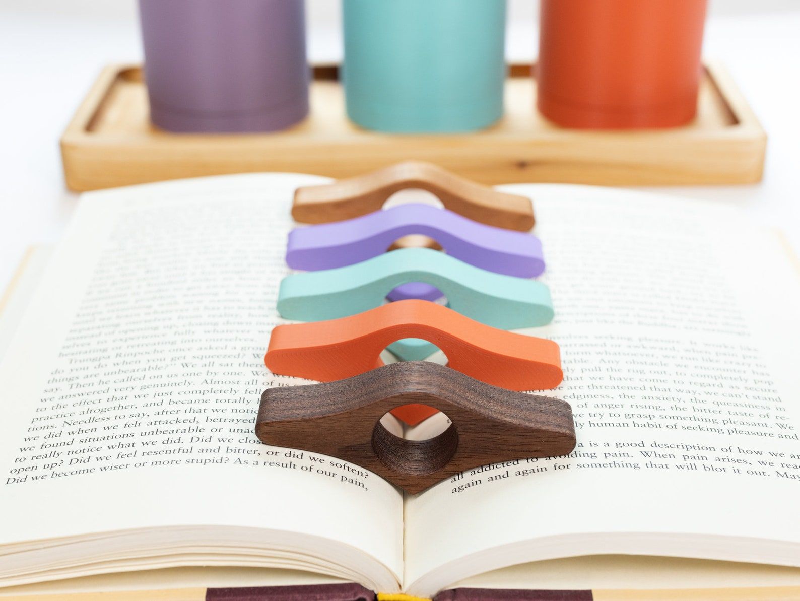 Set of four book page thumb holder in wood grain, turquoise, orange, and lavender