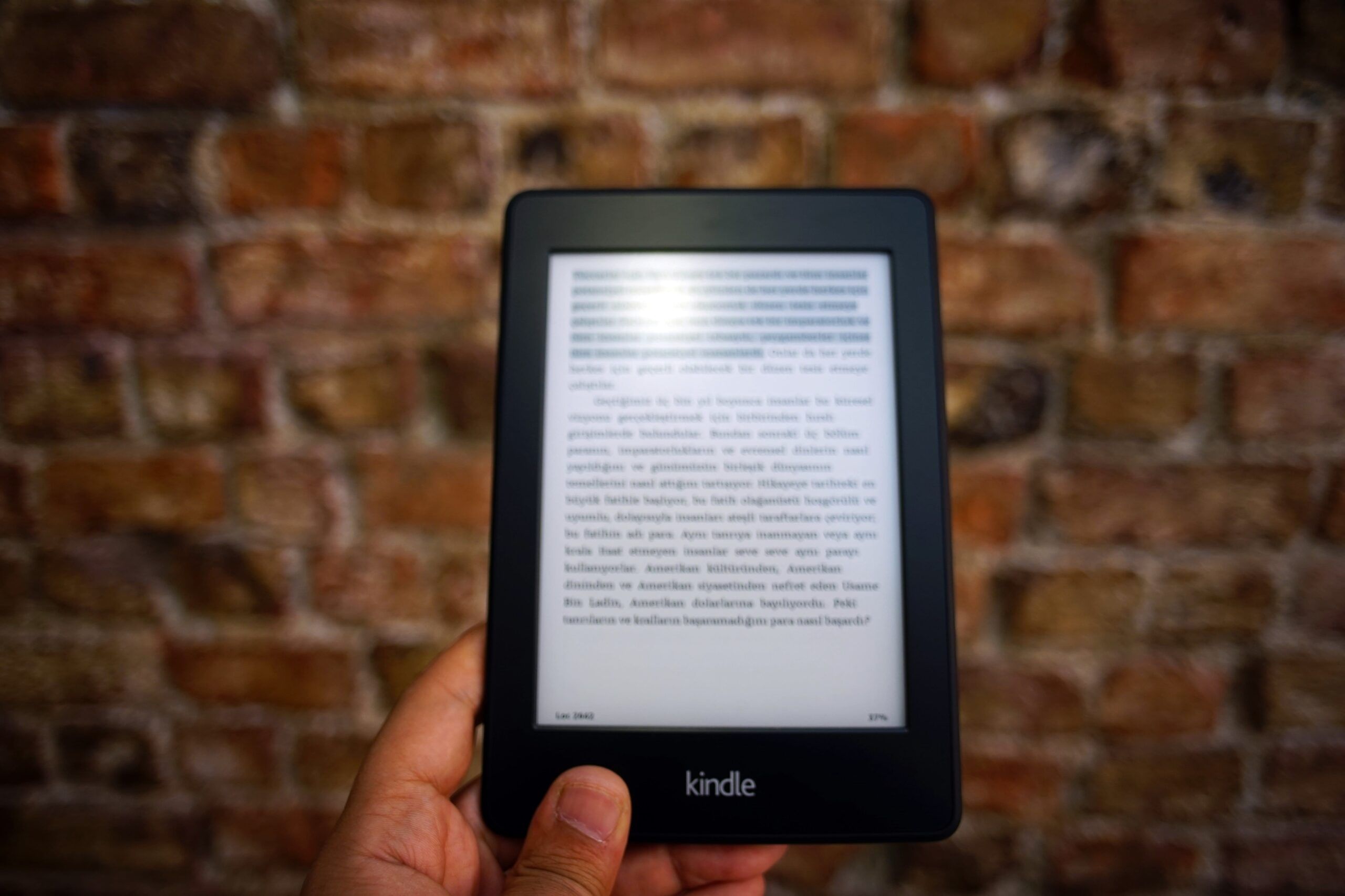 a tanned-skin hand holding a Kindle with text on it