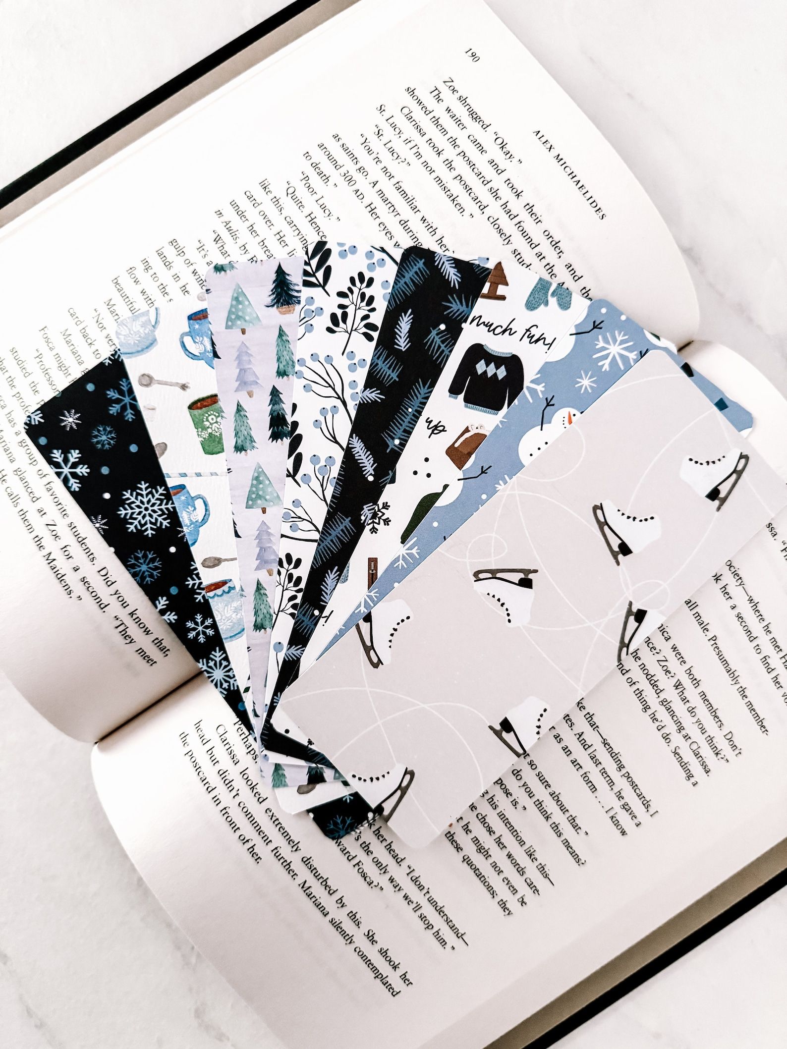 An array of seven bookmarks in blue hues that depict various winter activities