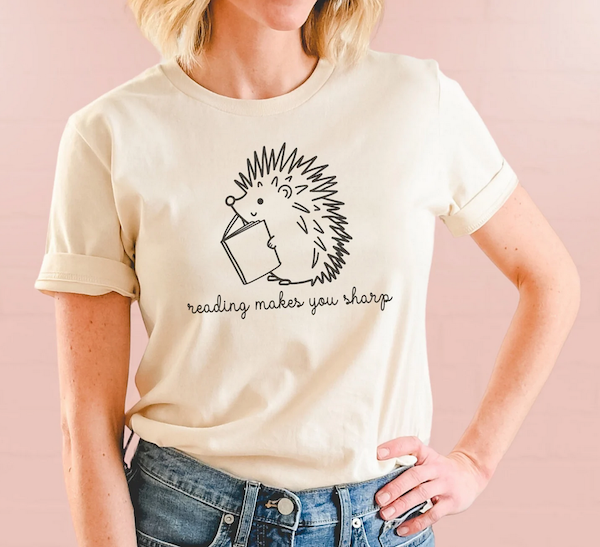 cream color tshirt with an illustrated hedgehog and text saying reading makes you sharp