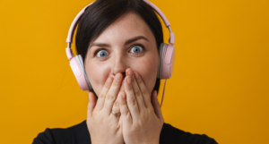 a woman wearing headphones covers her mouth in surprise