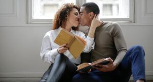 a couple kissing while holding books