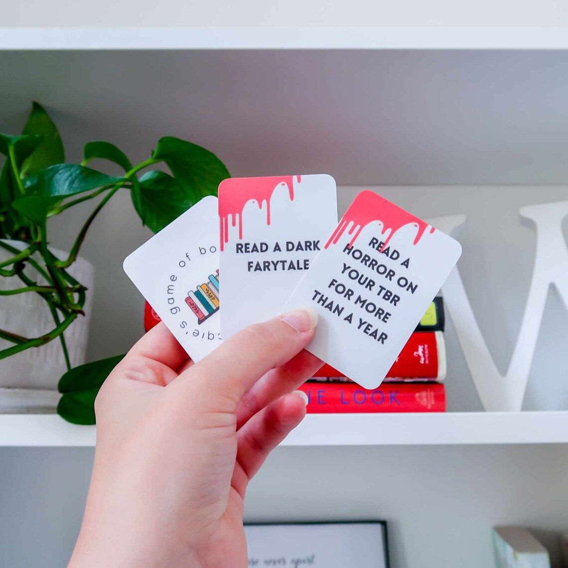 Hand holding three small cards that have reading prompts on them