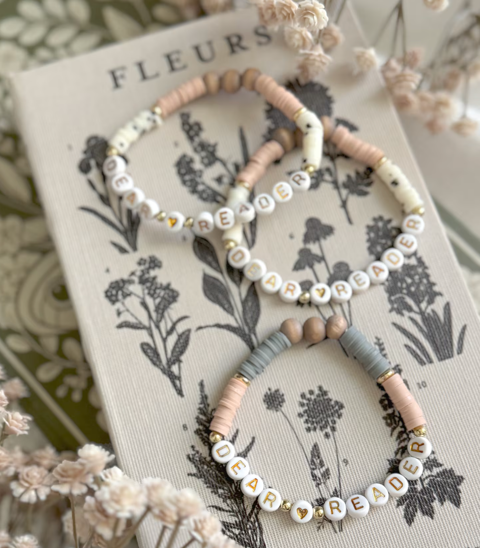 image of three friendship bracelets with the words "dear reader" in pastel colors. 