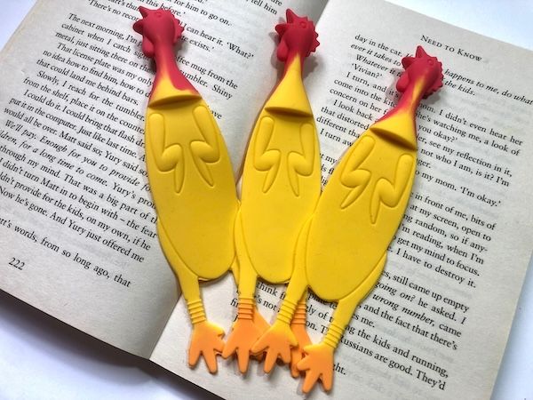 three yellow silicone chicken bookmarks inside an open book