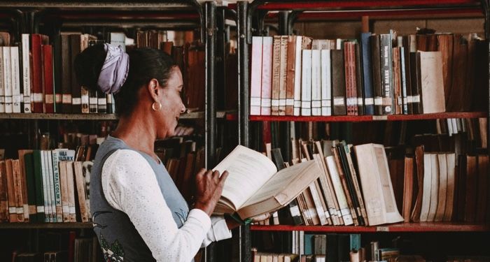 brown-skinned older woman reading a book