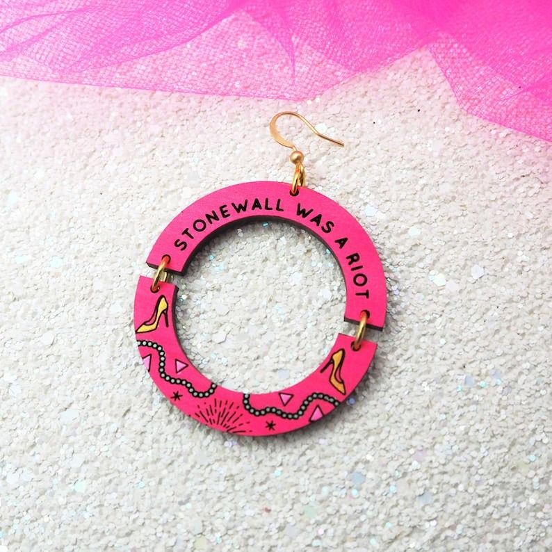 round wooden earrings with the text Stonewall Was a Riot
