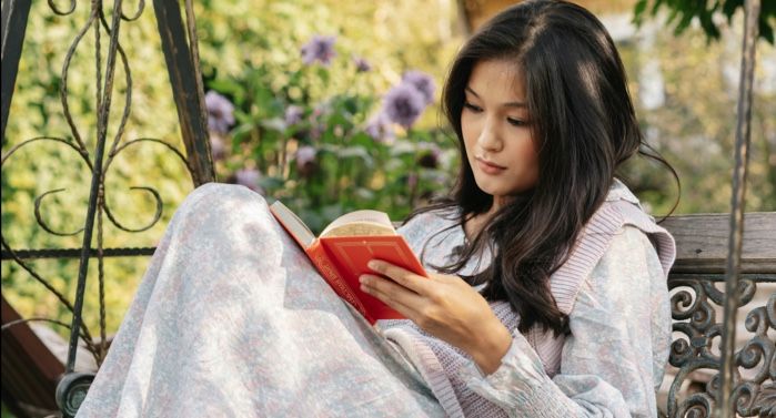 light-skinned Asian woman reading on a bench