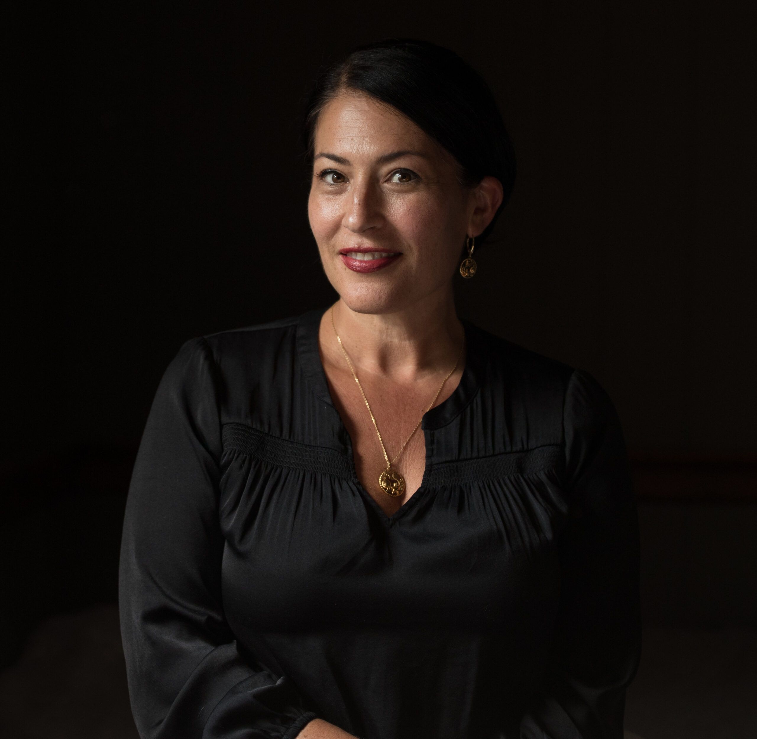 author Ada Limon, a brown-skinned woman in a black long-sleeved top