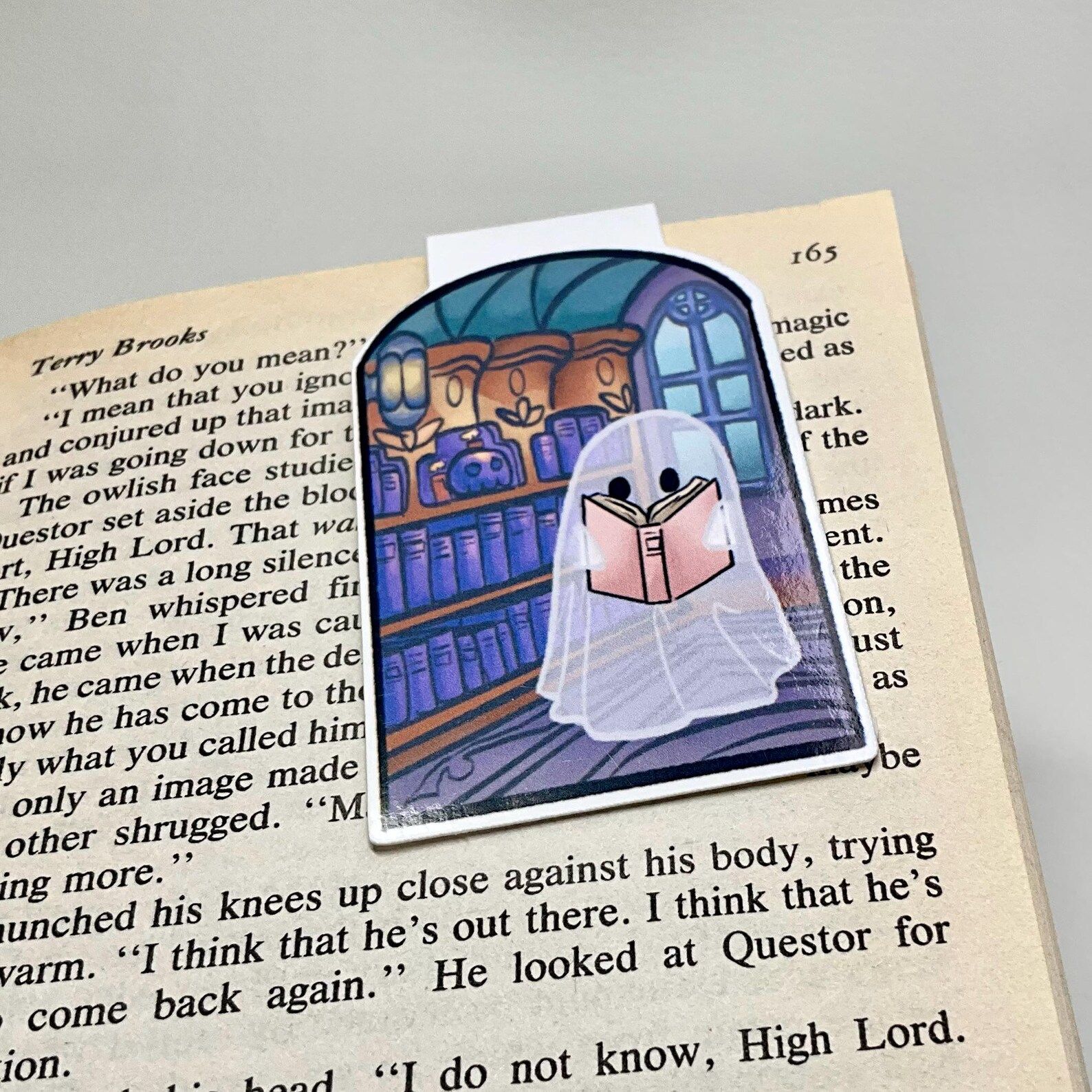 Image of a magnetic bookmark. It has a ghost in a library. 