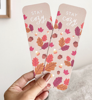 a book mark in fall colors with an illustration of autumn leaves that says stay cozy