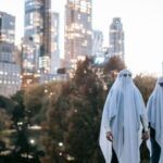 a couple holding hands in a city wearing white sheets over their heads to look like ghosts